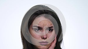 A cute young woman makes a sad face on a white background