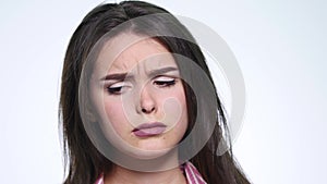A cute young woman makes a sad face on a white background