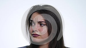 A cute young woman makes a sad face on a white background