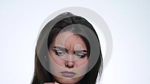 A cute young woman makes a sad face on a white background