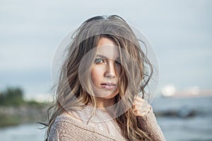 Cute young woman outdoor portrait. Pretty female face with natural makeup and long curly haircut