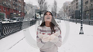 Cute young woman outdoors enjoying snow in city park in winter