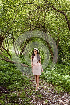 Cute young woman in pink dress standing in flowers garden outdoors. Beautiful girl outdoor portrait