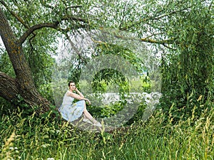 Cute young woman sitting on a beautiful, flowering tree