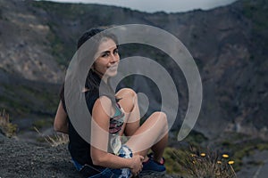 Cute young woman sitting happily smiling on a viewpoint in Irazu Volcano National Park