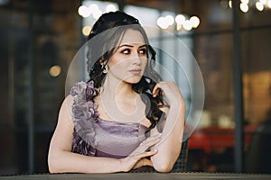 Cute young woman sitting in street cafe in front of restaurant windows