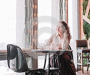 Cute young woman sitting at a table in a cafe
