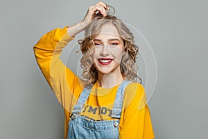Cute young woman smiling on gray background