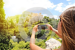 Cute young woman takes a picture of the Acropolis, Athens, Greece. Famous ancient Greek Acropolis is the main landmarks of Athens