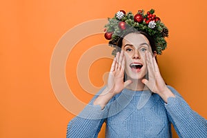 Cute young woman in traditional Christmas wreath, openes mouth wide, screams joyfully, Xmas is coming photo