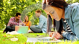 Cute young woman using her tablet while lying on a lawn