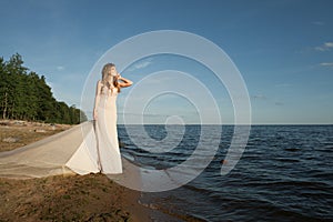 Cute young woman waiting and looking at horizon on sea coast background