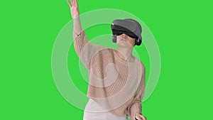 Cute young woman walking and using interactive VR headset on a Green Screen, Chroma Key.