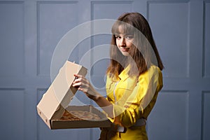 Cute young woman in a yellow jumpsuit delivering pizza.