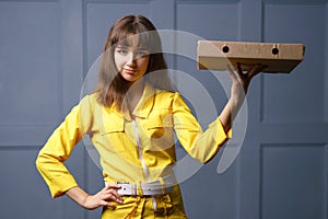 Cute young woman in a yellow jumpsuit delivering pizza.