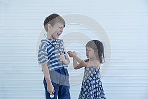 Cute younger sister holding syringe pretend to inject vaccine in her brother`s arm