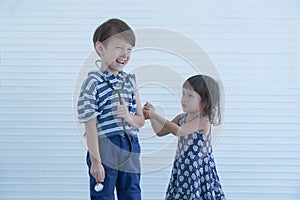 Cute younger sister holding syringe pretend to inject vaccine in her brother`s arm