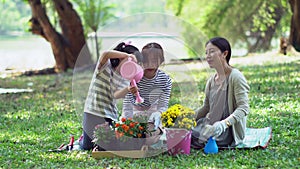 Cute youngest daughter planting flowers with mother and oldest sister