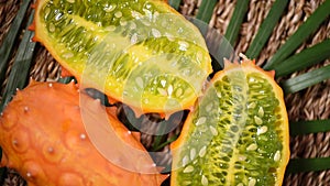 Cuted african horned melon on rotating background. Top view. Exotic Kiwano melon fruits, tropical palm branch. Vegan and