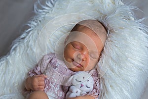 Cutest newborn girl sleeping sweetly on photosession