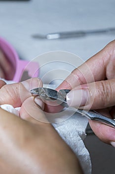 Cuticle Cutting. Woman hands receiving manicure and nail care procedure. Close up concept. Manicurist pushing cuticles