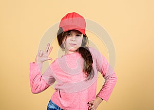 Cutie in cap. Girl cute child wear cap or snapback hat beige background. Little girl wearing bright baseball cap. Modern