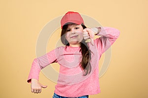 Cutie in cap. Kids fashion. Girl cute child wear cap or snapback hat beige background. Little girl wearing bright