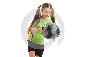 Cutie little girl in green uniform with soccer ball in hands