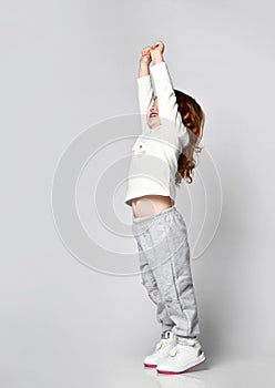 Cutie toddler little girl in sportswear doing stretching exercise