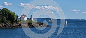 Cutler Island Lighthouse with sailboats floating by. Maine coast Camden