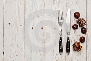 Cutlery and chestnut on a rustic wooden table