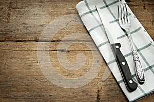 Cutlery and fork with napery on wooden background.