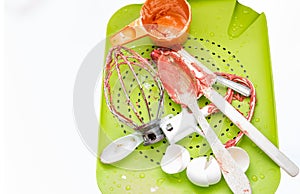 Cutlery lying in a drain tray with cookie dough on it ready to be washed.