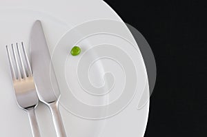 Cutlery and a pea on the plate