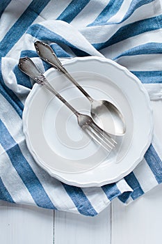 Cutlery, porcelain plate and white linen napkin