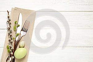 Cutlery set and beautiful willow branches on white wooden table, top view with space for text. Easter celebration