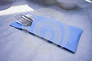 Cutlery set with fork, knife, and tissue wrapped inside a blue paper envelope photo