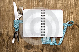 Cutlery tied with measuring tape and blank notebook