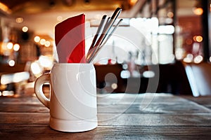 Cutlery on a wooden table in a ceramic beer mug