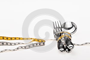 Cutlery wrapped with a tape measure, symbol for a diet