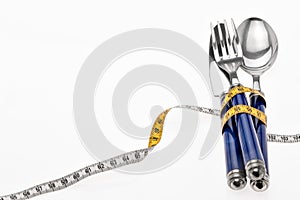 Cutlery wrapped with a tape measure, symbol for a diet