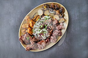 cuts of meat barbecue kebabs grilled pork and beef and chicken on a plate with onions and vegetables and potatoes