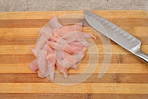 Cutted chicken fillet with knife on a wooden chopping board, ski