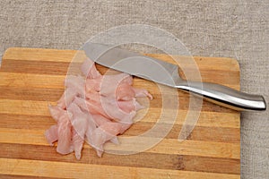 Cutted chicken fillet with knife on a wooden chopping board, ski