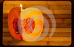 Cutted fresh orange big pumpkin on bamboo board, close up. Organic agricultural product, ingredients for cooking