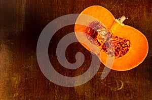 Cutted fresh orange big pumpkin on wooden background, close up. Organic agricultural product, ingredients for cooking