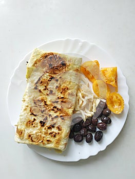 Cutted lavash pieces with vegetables on the plate. Burek with tomato and black olives. Yufka