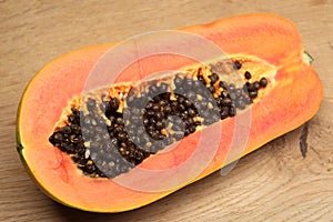 Cutted off ripe tasty papaya fruit with juicy orange pulp indoor studio photo  on wooden background top view close up