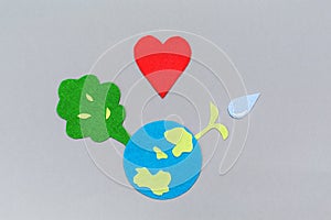 Cutted out of felt the planet Earth and tree with a watered plant sprout. Copy space. Gray background. Flat lay. Earth Day
