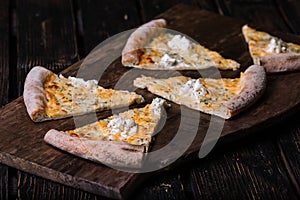 Cutted Quattro formaggi pizza on wood background